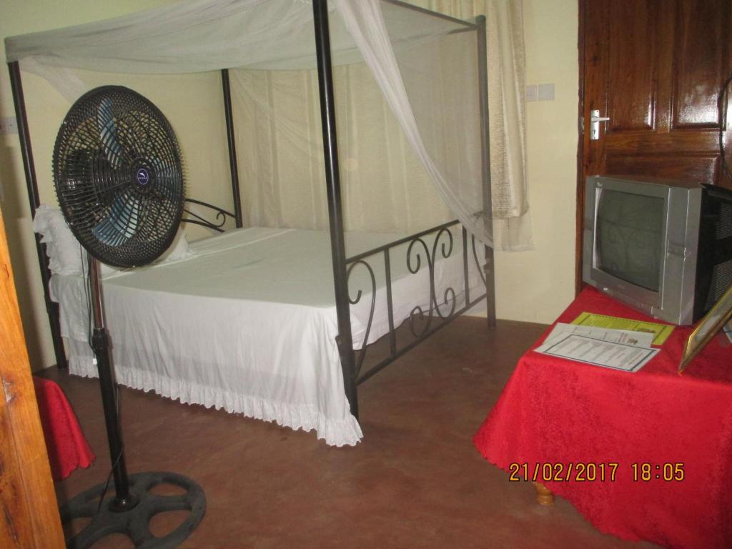 a bedroom with a bed with a fan and a tv at Fanaka Safaris Campsite & Lodges in Mto wa Mbu