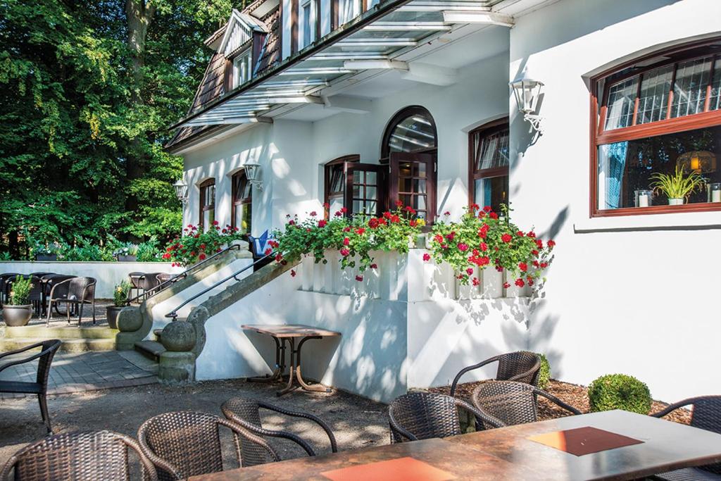 an outdoor patio with tables and chairs and flowers at Hotel Münnich in Münster