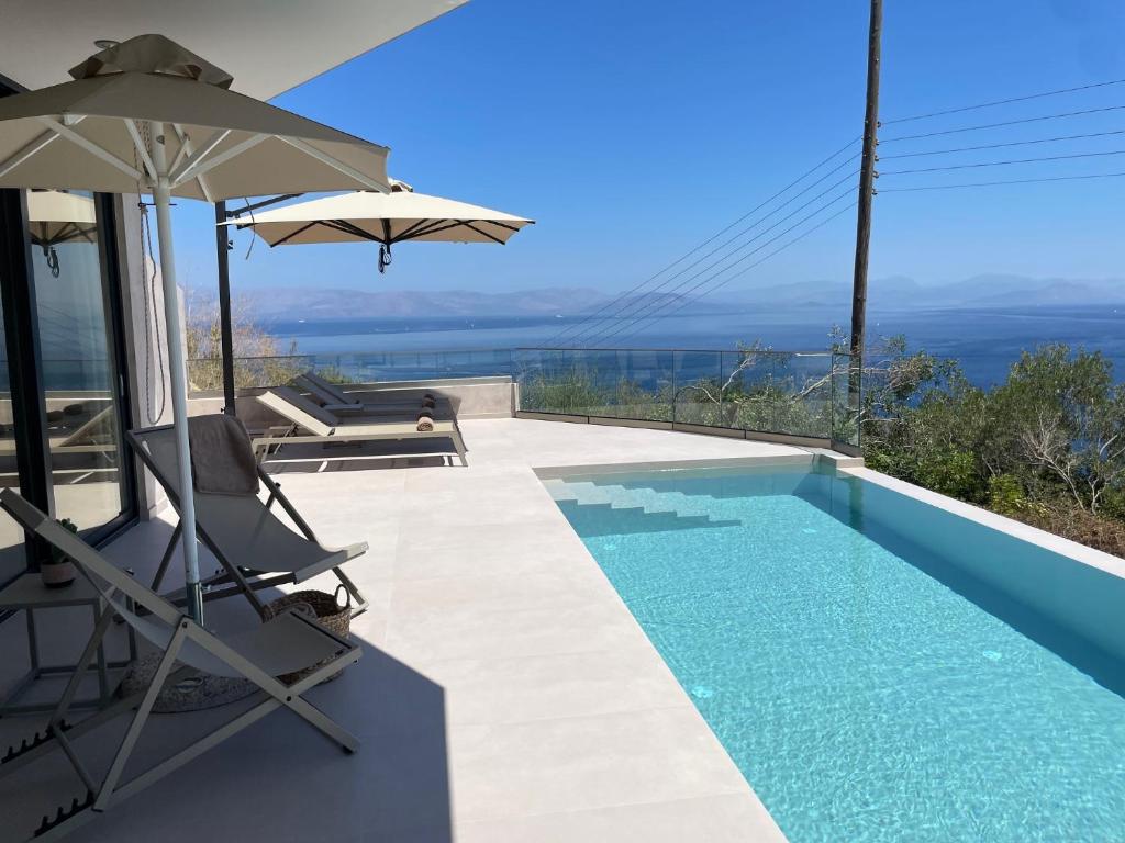 a swimming pool with two chairs and an umbrella at Nomade Villas in Agios Ioannis Peristerion