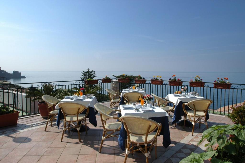 un patio con mesas y sillas con el océano en el fondo en Hotel Baia Verde, en Maiori