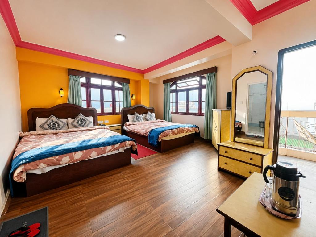 a large room with two beds and a mirror at Hotel Darjeeling palace in Darjeeling
