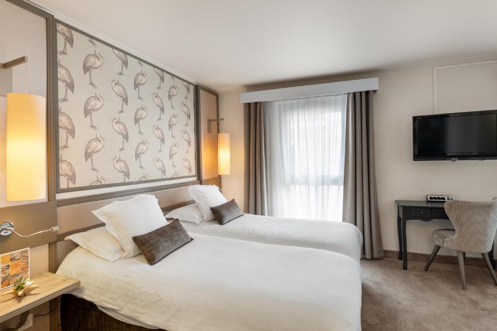 a hotel room with two beds and a flat screen tv at Hotel America in Cannes