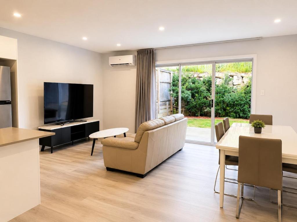 a living room with a couch and a tv and a table at 20 Pimpama Home in Pimpama
