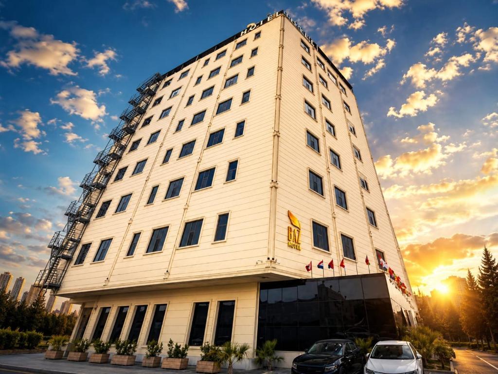 a tall white building with cars parked in front of it at BAZ Hotel University District in Baghdād