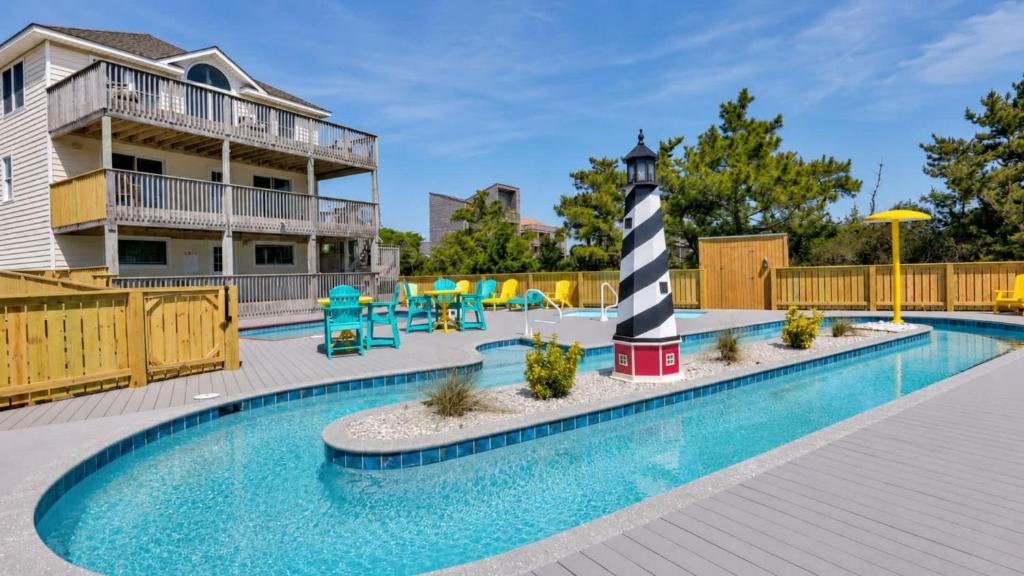 a swimming pool with a lighthouse next to a house at Rio Rodanthe Lazy River Kiddie Pool Oceanfront Elevator in Rodanthe