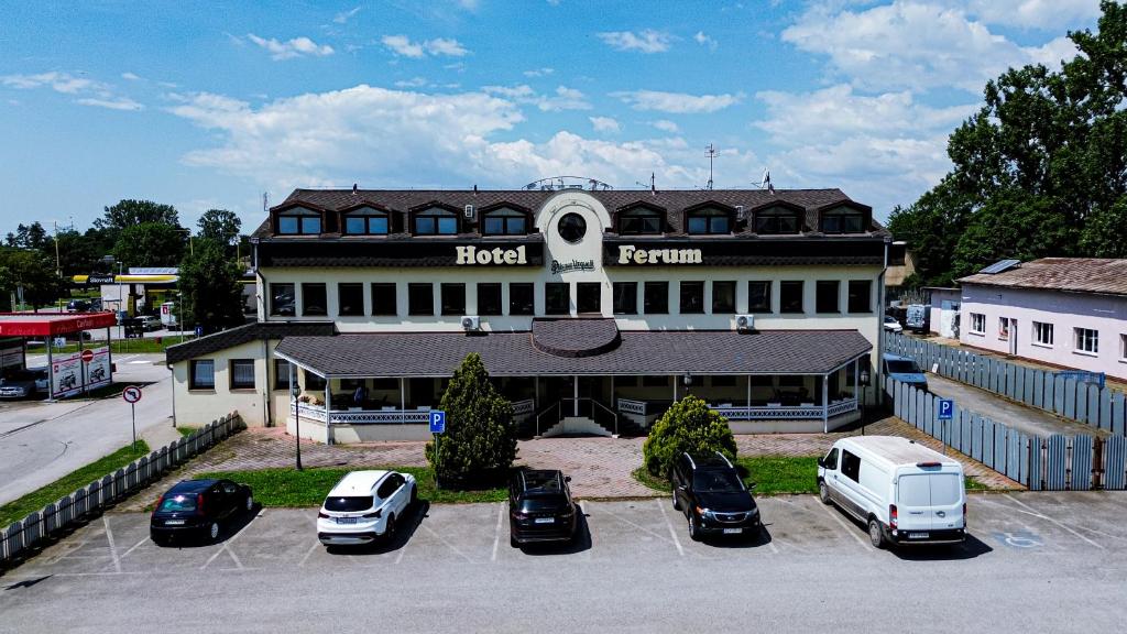 a large building with cars parked in a parking lot at Hotel Ferum in Šaca