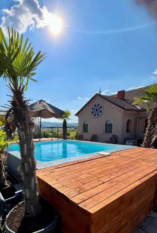 a swimming pool with a wooden deck next to a house at Chateau Vincze in Sátoraljaújhely