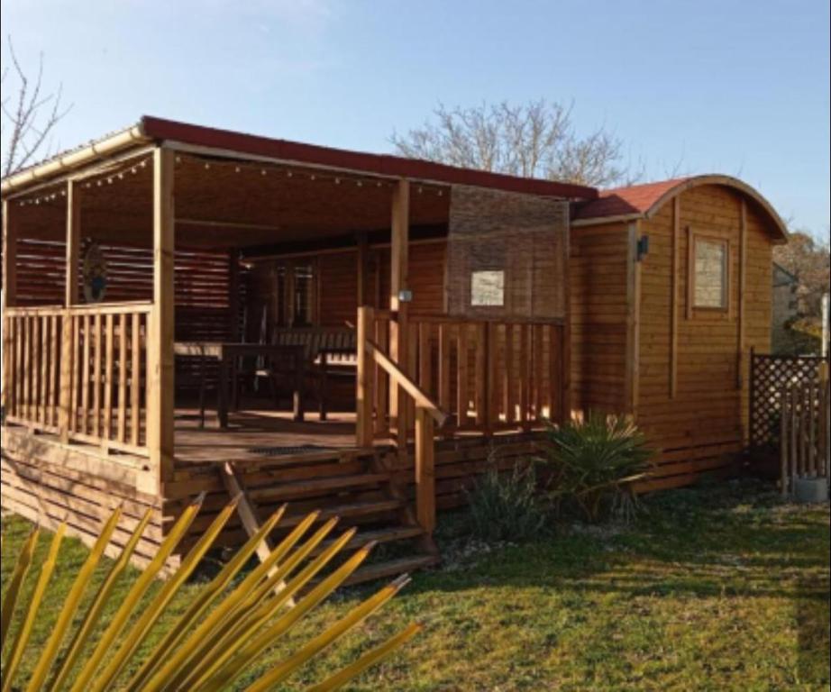 a wooden cabin with a porch and a deck at roulotte en bois in Ranton