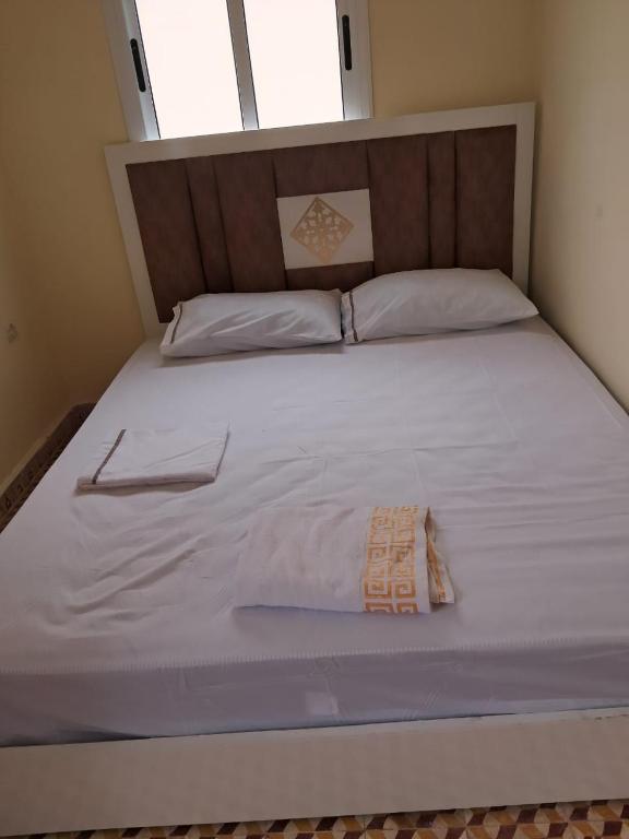 a large white bed with a wooden head board at casa celia in Asilah
