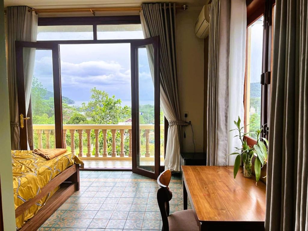 a bedroom with a balcony with a bed and a wooden table at Family-friendly accomodation with sea view in Kaôh Kon