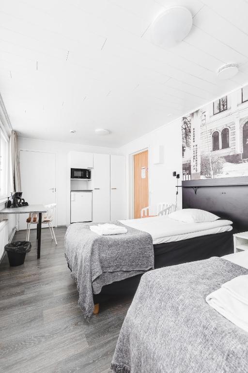 a white room with two beds and a desk at LODGE Aparthotel Raahe in Raahe