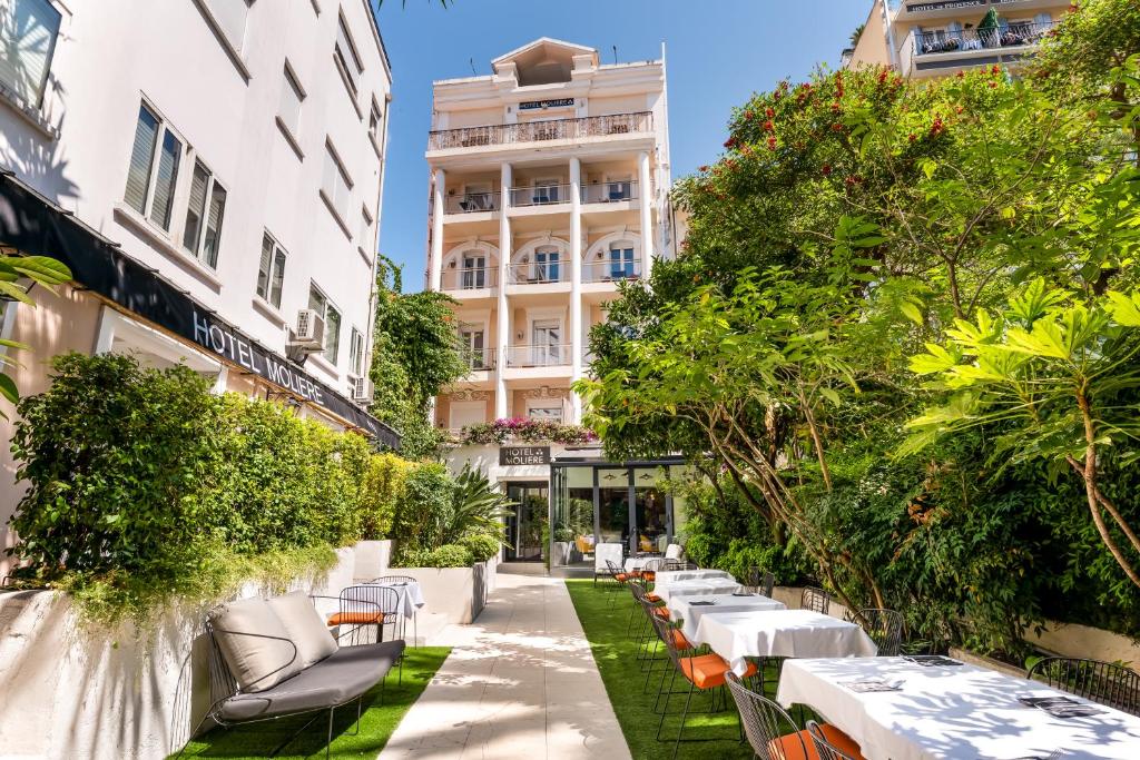 a courtyard with tables and chairs and trees at Hotel Molière in Cannes