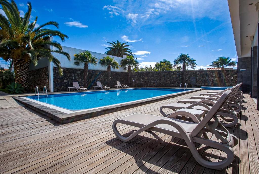 a row of lounge chairs next to a swimming pool at Antillia Hotel in Ponta Delgada