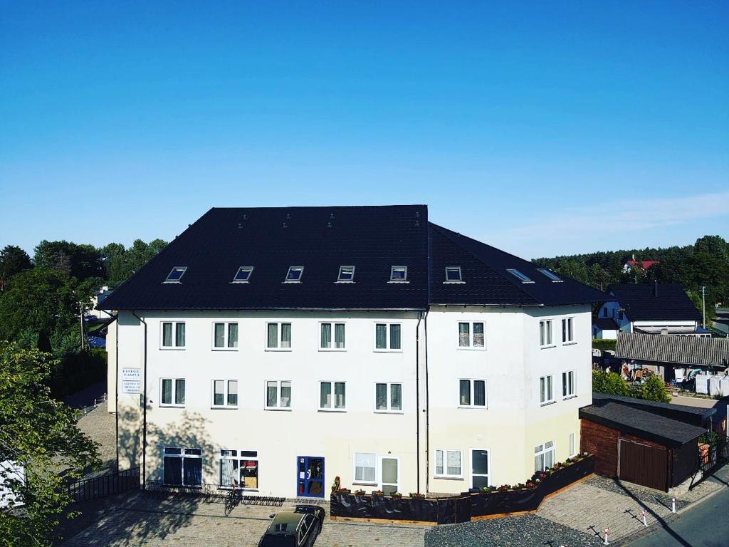 a large white building with a black roof at Willa Białe Piaski Pokoje i Noclegi Białogóra in Białogóra