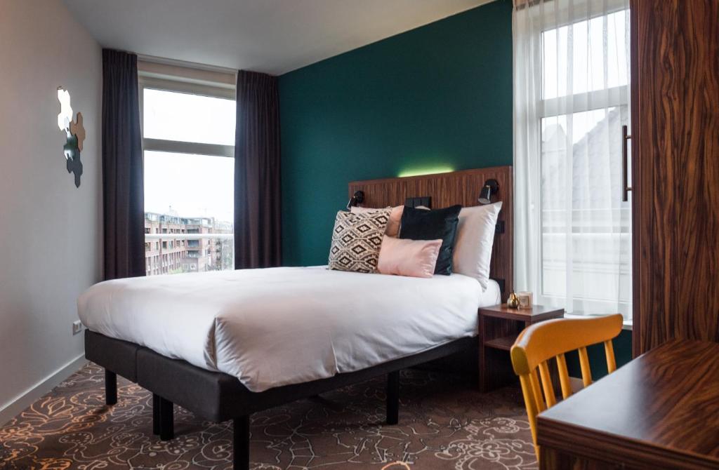 een slaapkamer met een groot bed met een groene muur bij Linden Hotel in Amsterdam