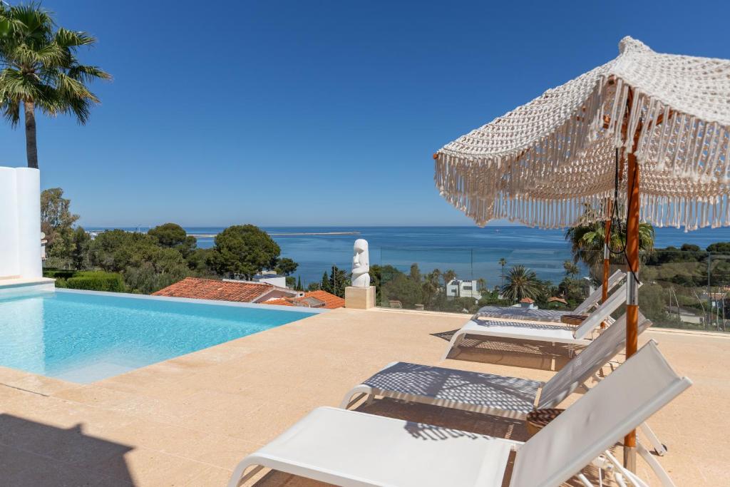 a swimming pool with two chairs and an umbrella at Atalaya Boutique in Denia