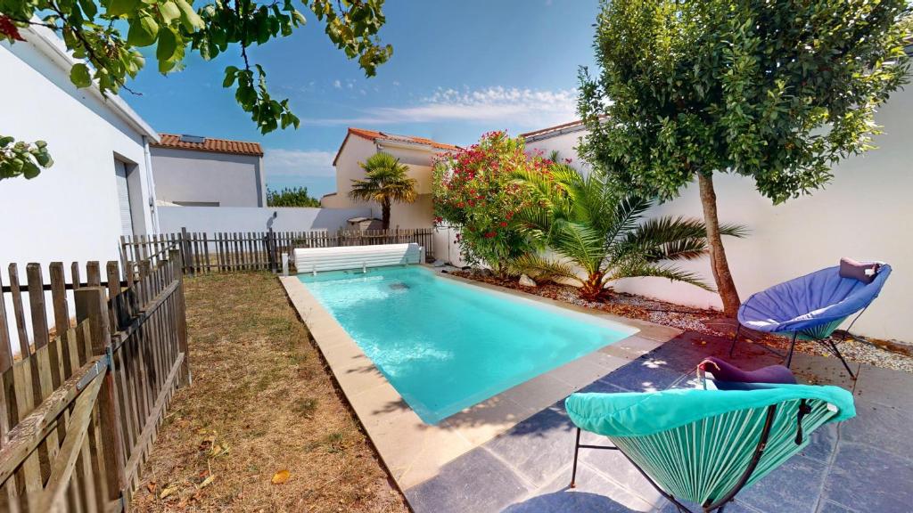 a swimming pool with two chairs and a house at La Villa Estran in Saint-Gilles-Croix-de-Vie