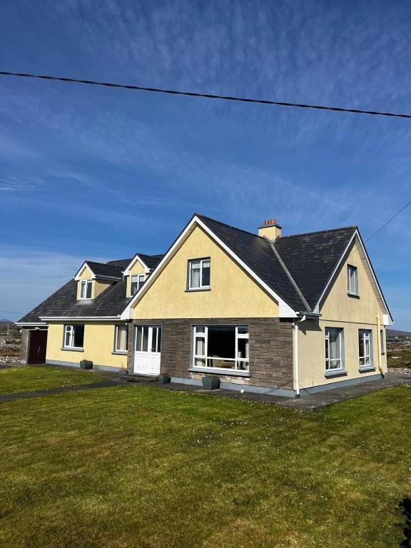 a large yellow house with a black roof at Teach na hAirde in Carna