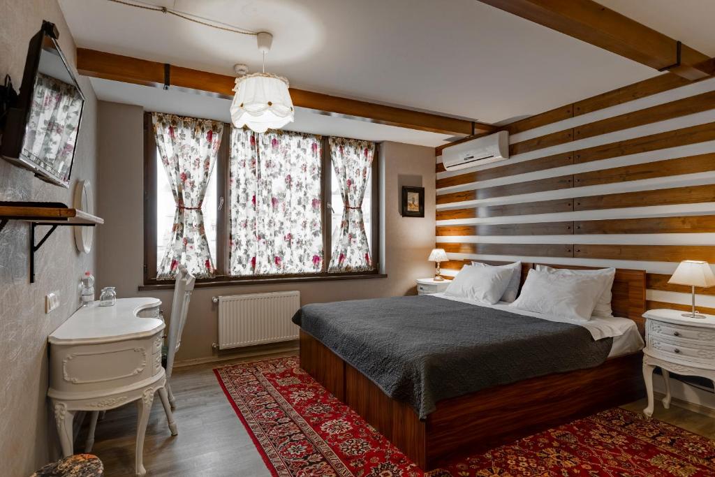 a bedroom with a bed and a desk and a window at Hotel Beli in Tbilisi City