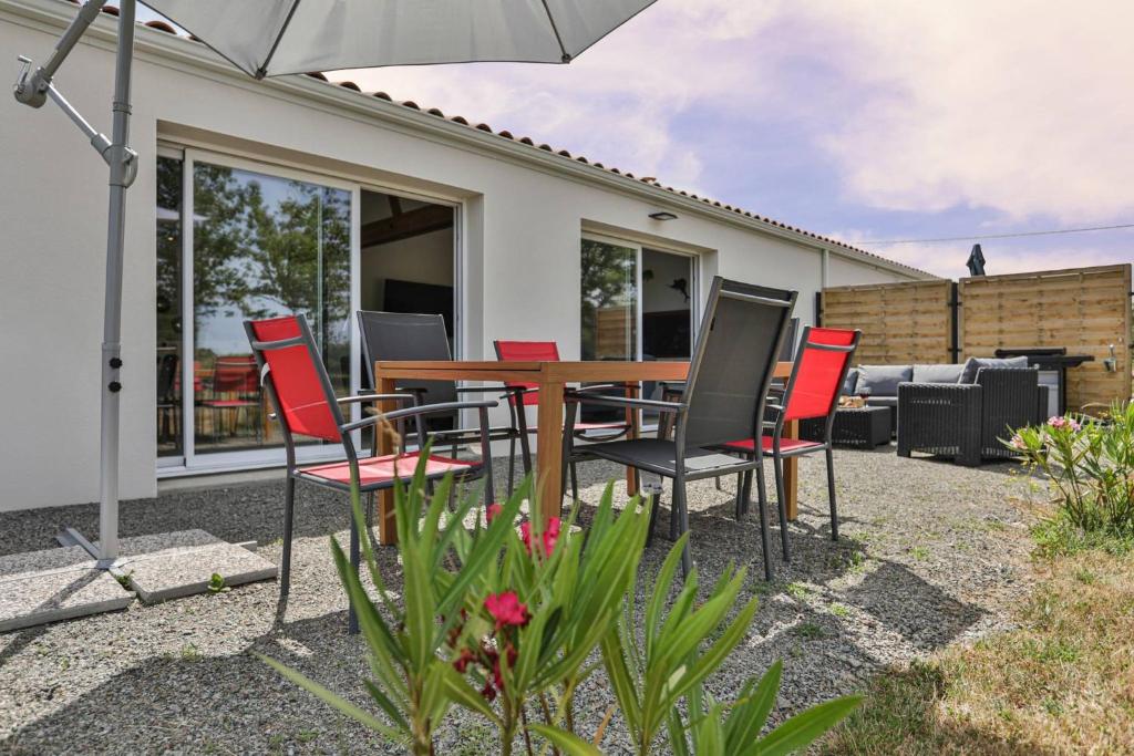 a table and chairs with an umbrella in front of a house at L'échappé Belle du Bessay in Avrillé