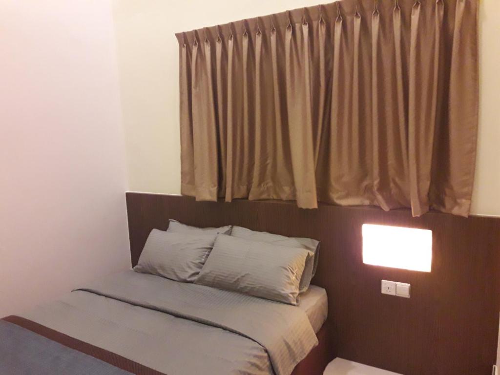 a small bed in a room with a window at De Benz Inn in Malacca