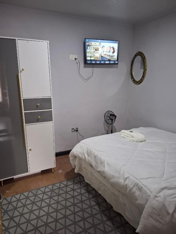 a bedroom with a bed and a tv on the wall at Elimisam cabin in Kitwe