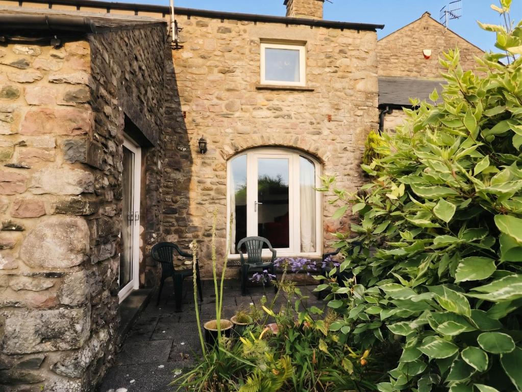 an external view of a stone house with a garden at The Spinney in Milnthorpe