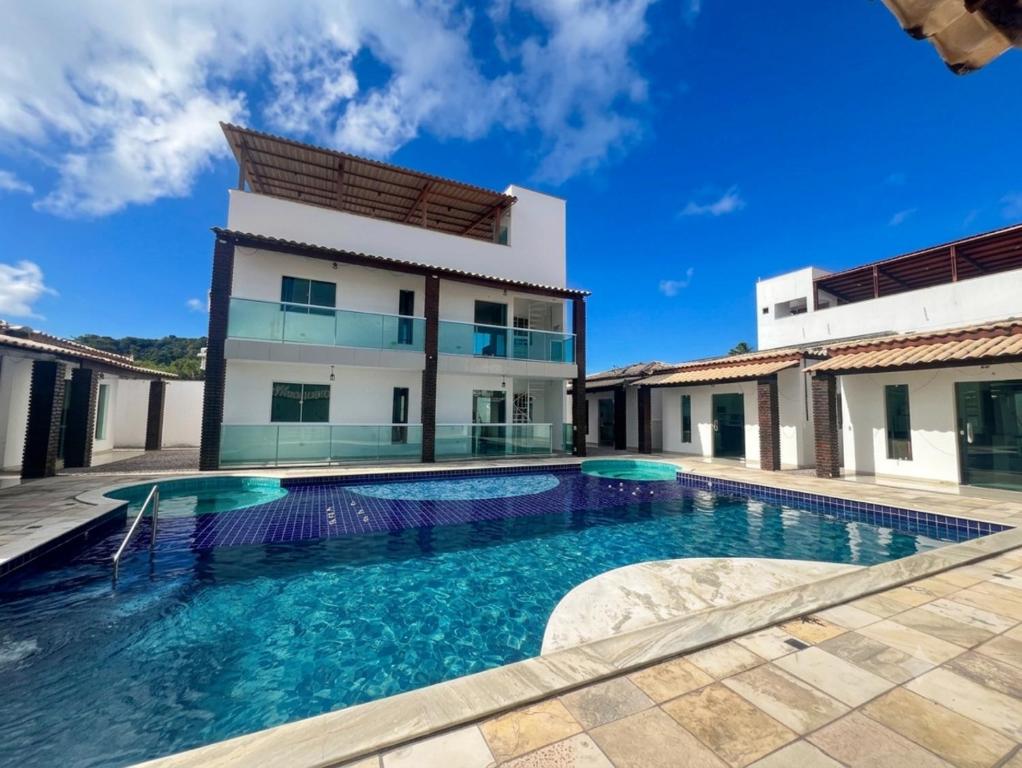 a villa with a swimming pool in front of a building at Vila Bangalô in São José da Coroa Grande