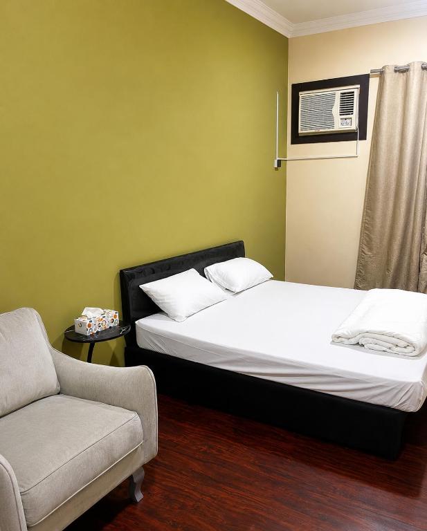 two beds in a room with a couch and a chair at Liva Residency in Salalah