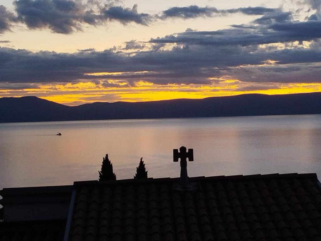 a cross on the roof of a building with a sunset at Apartment Hribar in Labin