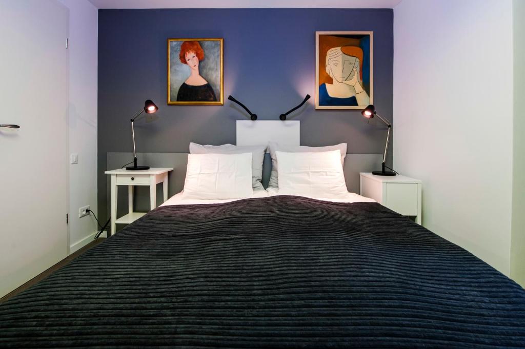 a bedroom with a large bed with three paintings on the wall at Apartments Aalvar and Aalto in Rovinj