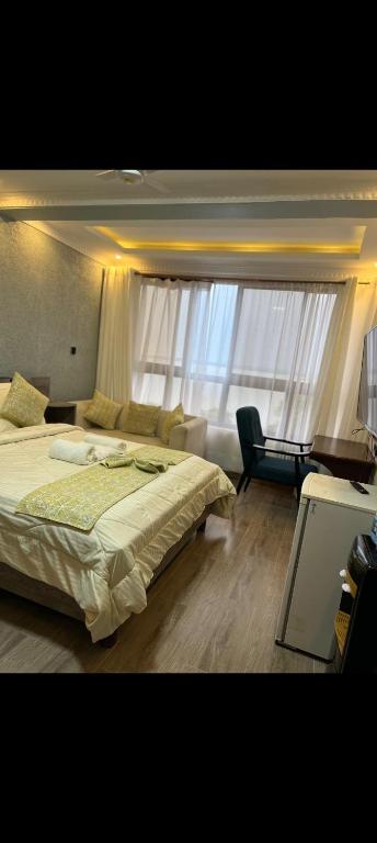 a bedroom with a bed and a chair and a window at Sky Beach Resort Ltd in Kisumu