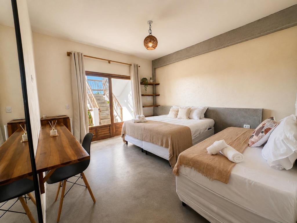 a bedroom with two beds and a desk and a window at The Wave Kite House in Guriú