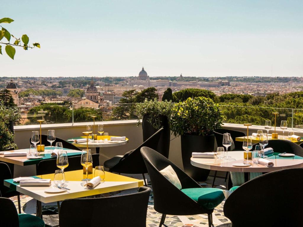 ein Restaurant mit Tischen und Stühlen und Blick auf die Stadt in der Unterkunft Sofitel Roma Villa Borghese in Rom