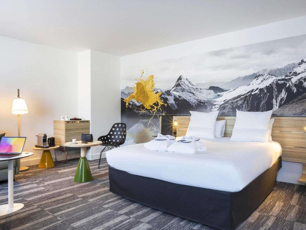 a hotel room with a large bed with mountains on the wall at Novotel Annecy Centre in Annecy