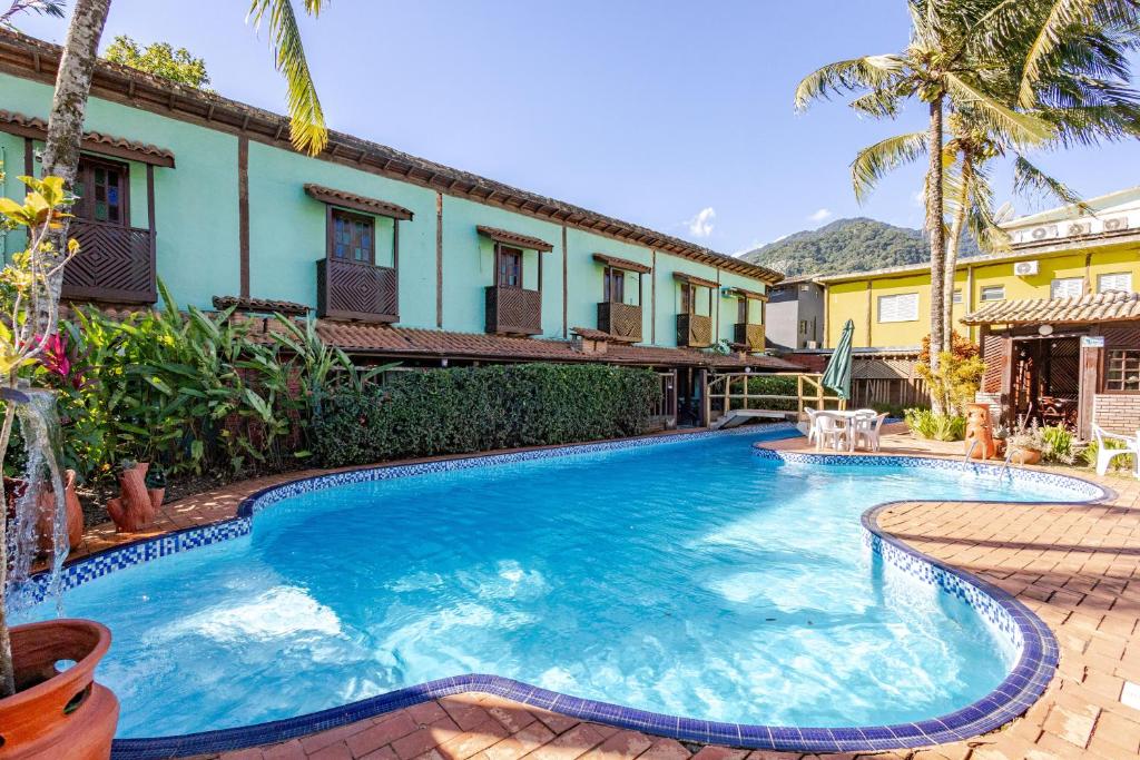 a swimming pool in front of a house at Pousada Lua Chalés in Maresias