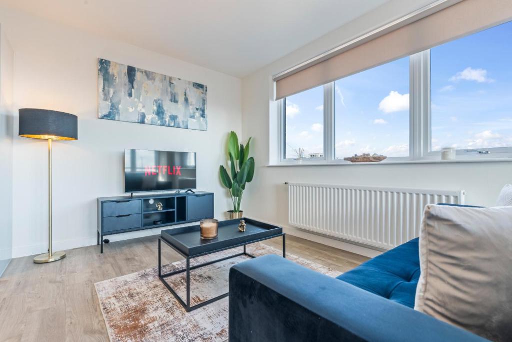 a living room with a blue couch and a table at Thameside Suite | Free Parking | 2 BR | Heathrow in Staines