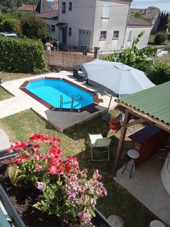 a swimming pool with an umbrella and some flowers at Mady in Villeneuve-sur-Lot