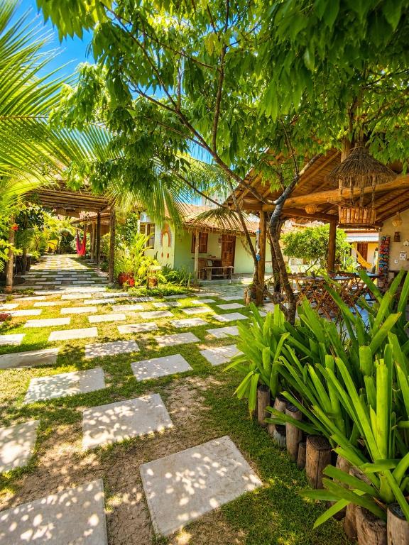 a garden with a pathway and trees and a building at Vila Uryah in Caraíva