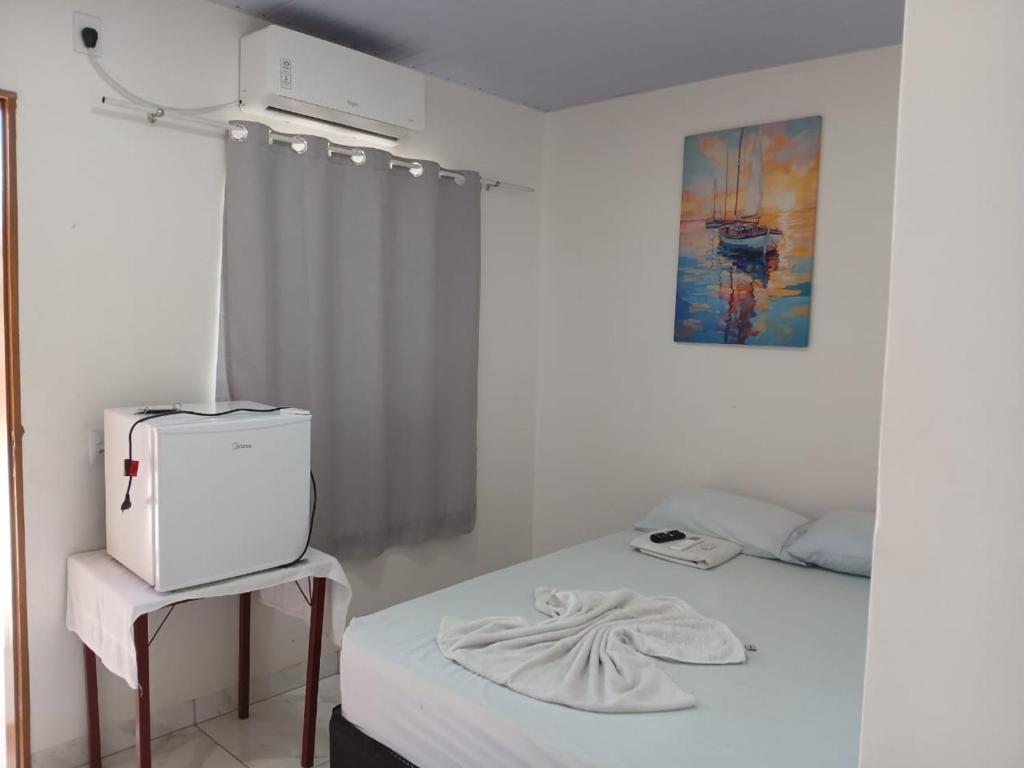 a white room with a bed and a microwave at Hotel Dunil in Araguaína