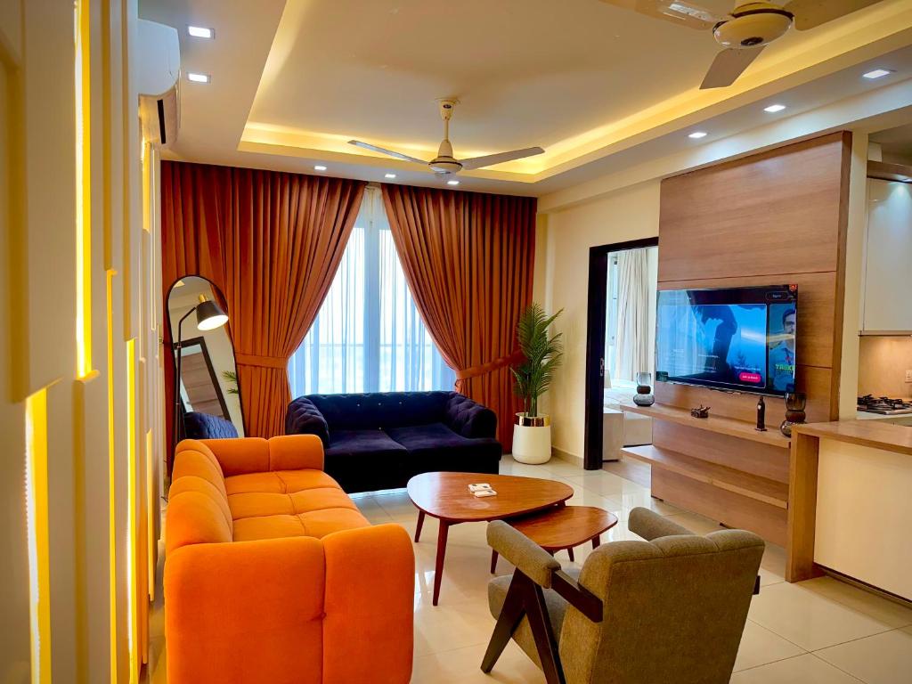 ein Wohnzimmer mit einer orangefarbenen Couch und einem Fernseher in der Unterkunft Executive Penta Studio Luxury Apartments DHA Lahore in Lahore