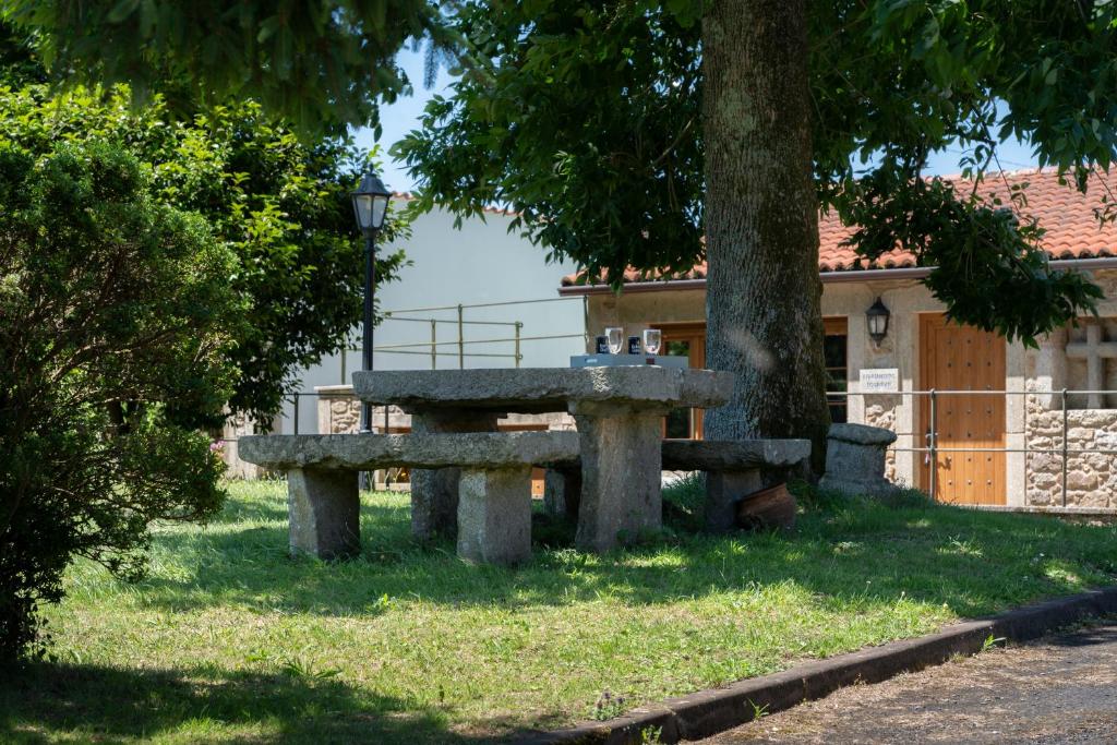 a stone bench sitting under a tree in front of a building at Apartamento Pescadeira de Agar in Rego de Santa Marina