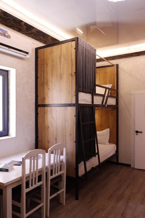 a room with a bunk bed and a table and chairs at AL-BUKHARI Boutique Hostel in Bukhara