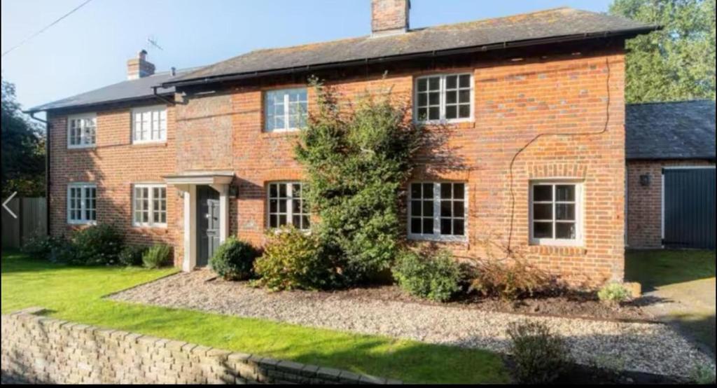 a brick house with a stone wall in front of it at Riverside Cottage Sleeps 8 with Parking in Marlborough
