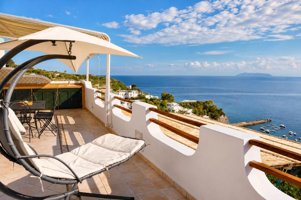 a balcony with chairs and an umbrella and the ocean at Maridea - La Terrazza in Ponza
