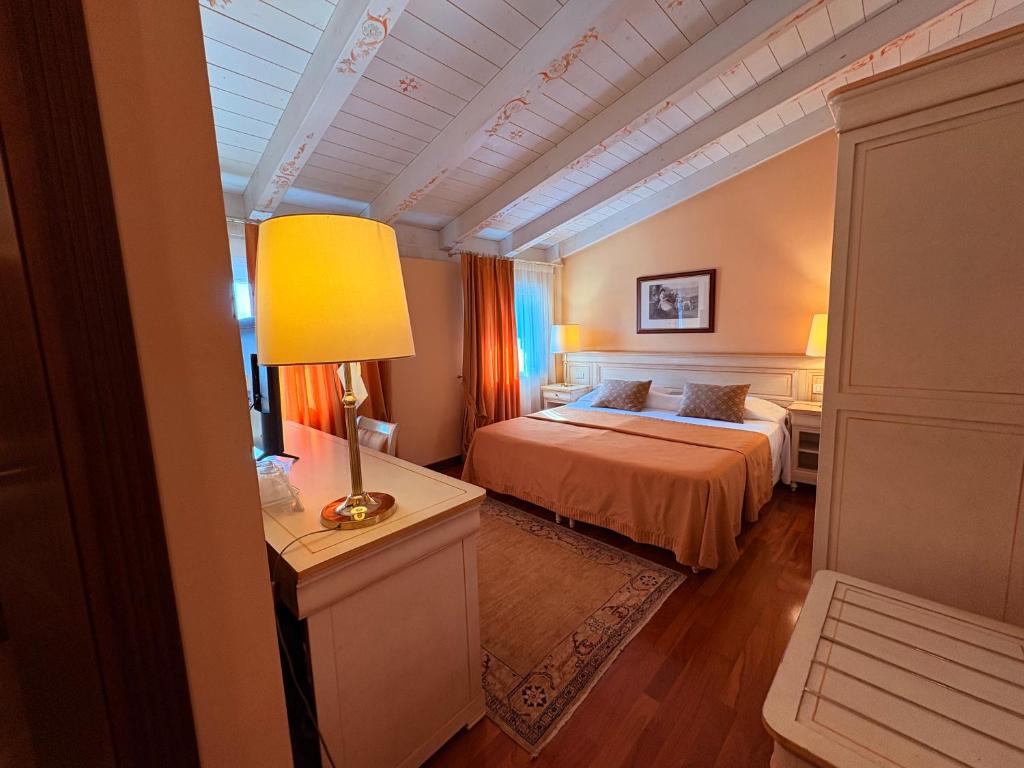 a bedroom with a bed and a lamp on a table at Le Muse Hotel in San Bonifacio