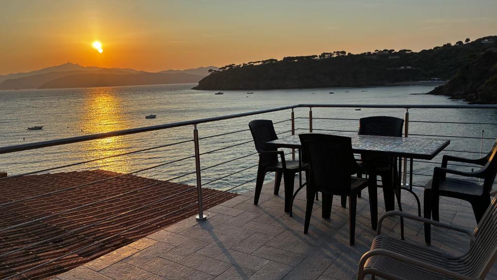 a table and chairs on a balcony with the sunset at Pareti di mare in Capoliveri