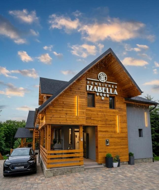 a building with a car parked in front of it at PENSIUNEA IZABELLA, Vila Cocket in Topliţa