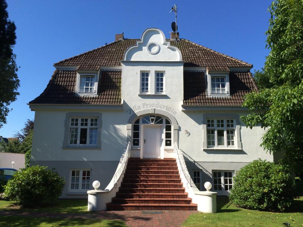 a large white house with stairs leading up to it at Villa Friedericia - Appartment 1 in Wyk auf Föhr
