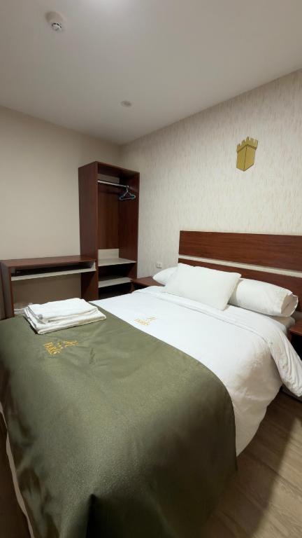 a bedroom with a large bed with a green blanket at Hotel Residencial Paris in Arequipa